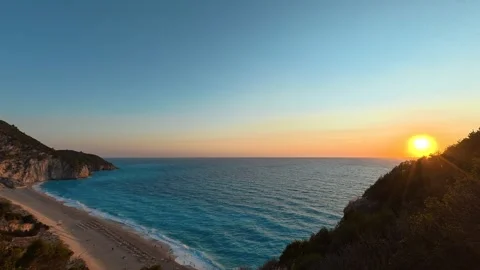 Sun dips behind cliffs, painting sky in warm gold. Milos Beach Sunset Greece Stock Footage 344093614