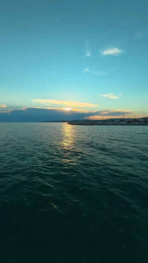 Sun dips behind distant shore. Trani Ammouda, Greece. Vertical Stock Footage 339630339
