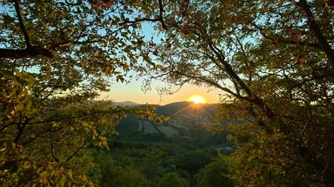 Sun dips behind forested hills, framed by autumn trees. Boracki krs Serbia 動画素材 345005824