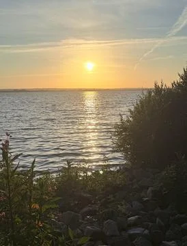 As the sun dips behind the horizon, casting a warm glow over the verdant land Foto stock