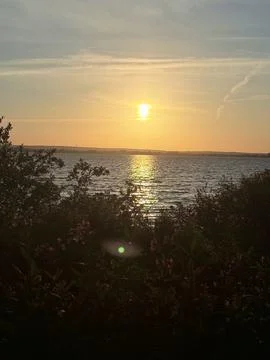 As the sun dips behind the horizon, casting a warm glow over the verdant land 写真素材