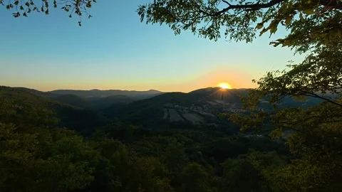 Sun dips behind tree line, casting golden glow. Boracki krs Serbia 動画素材 345005890