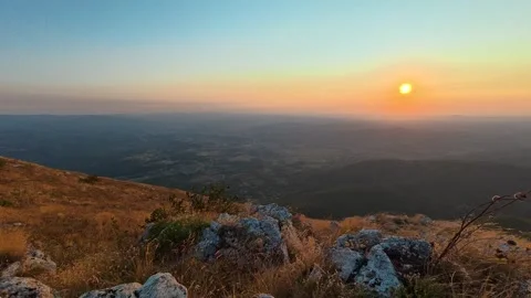 Sun dips below distant hills, casting golden light. Mount Rtanj sunrise Serbia Stock Footage 344686066