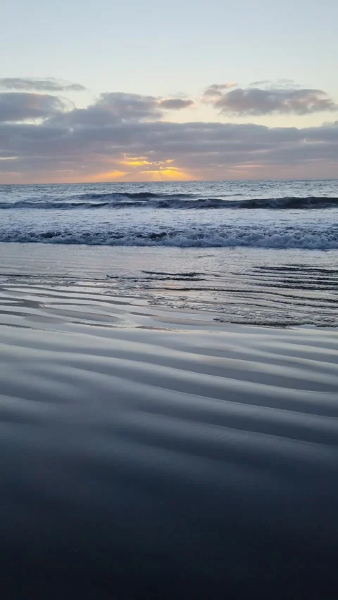 The sun dips below the horizon, casting beautiful colors over the Tenerife beach Stock Footage 307632602