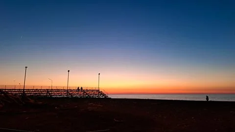 The sun dips below the horizon casting a warm golden glow across tranquil sea Stock Photos