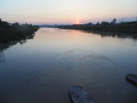 The sun dips below the horizon, illuminating the river as it gracefully Stock Photos