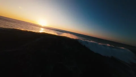 Sun dips low, casting golden glow on ocean waves Stock Footage 339789072