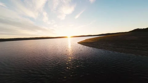 Sun dips low over calm lake surface Video stock 342169675