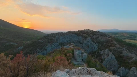 Sun dips low over rugged cliffs, painting sky in warm gold. Soko Grad, Serbia 動画素材 345897336