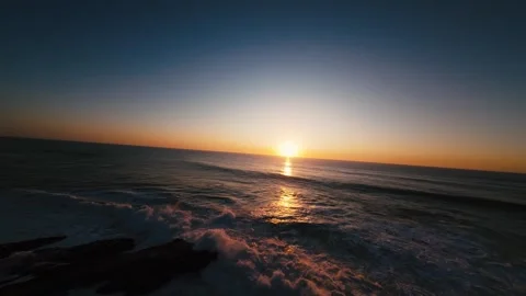 Sun dips low, painting sky and waves in gold and deep blue Stock Footage 339789097