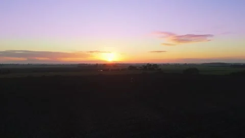 Sun dips low, painting sky in soft purple and gold. Fields stretch wide Stock Footage 343695823