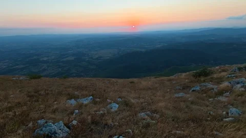 Sun dips low, painting sky in soft orange and blue. Mount Rtanj sunrise Serbia Stock Footage 344685300