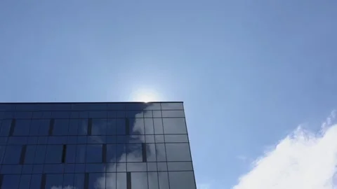 Sun disk appears from behind skyscraper wall with windows Stock Footage 134905394