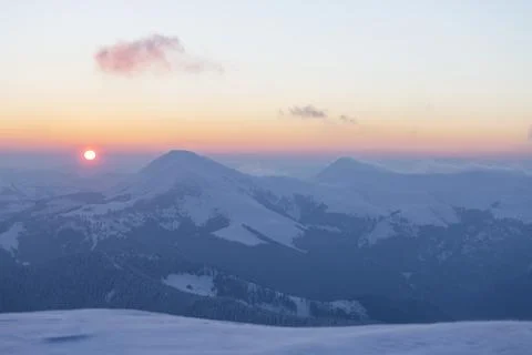The sun disk rises above a snow-covered mountain at dawn. Petros and Hoverl.. Foto stock