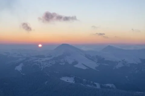 The sun disk rises above a snow-covered mountain at dawn. Petros and Hoverl.. 스톡 사진