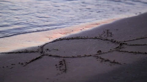 Sun drawn jn beach sand washed away by waves Video stock 66351477