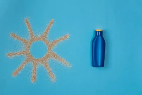 Sun drawn by the sand on blue background. Sunscreen on blue background. Top v Stock Photos