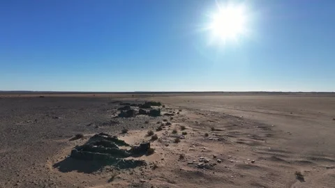Sun-Drenched Desert Plain with Ancient Stone Ruins and Sunburst Stock Footage 336617750