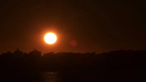 Sun falling behind buildings in a city. Time Lapse Stock Footage 296285216