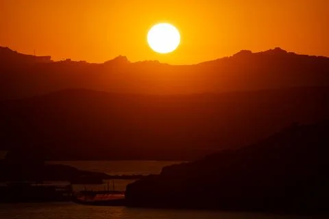 The Sun Falling Behind Mountain peak with sea foreground. A Spectacular golden Stock Photos