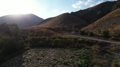 Sun flare over Chalus Road mountains lights a rocky track and dry slopes, Stock Footage 343907503