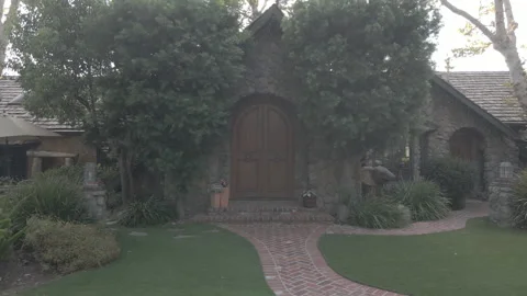 Sun flare over a stone cottage and garden with a brick path Stock Footage 345545904