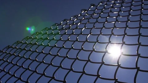 Sun flare shining through a black metal fence Stock Footage 104658880