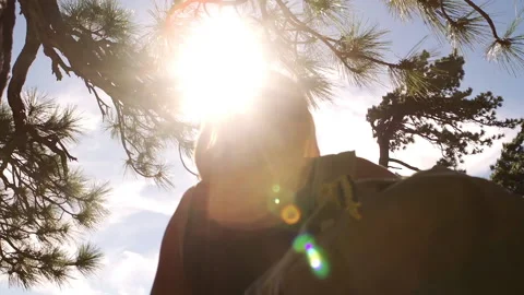 Sun flares and hand-held close up of woman with a backpack on a mountain top Stock Footage 138477072