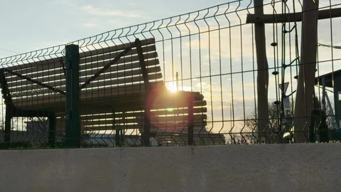 Sun Flares Behind Empty Park Bench and Playground Fence at Dawn Stock Footage 335153048