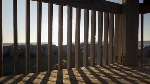 Sun flaring through ocean front gazebo railing Stock Footage 98458571