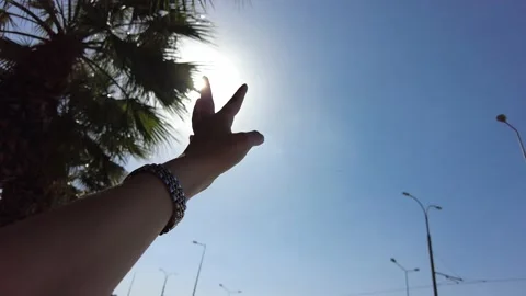 Sun glare and blue sky. Woman's hand is waving outstretched towards the sky. Stock Footage 219869829
