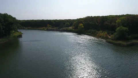 Sun glare on the surface of the river water. Trees on the shores of the lake Stock Footage 162104393