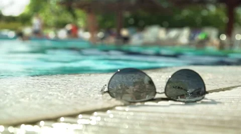 Sun glasses on the pool side and water reflection Stock Footage 64244148