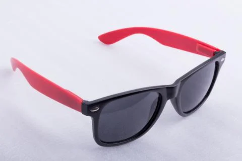 Sun glasses with red temples on a white surface Stock Photos
