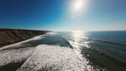 Sun glints on ocean waves near rocky shoreline Stock Footage 339803650