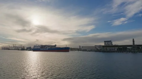 Sun glints off water near docked cargo ships Stock Footage 345261742