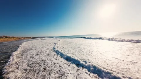 Sun glints off waves crashing on dark, rocky shore Stock Footage 339786792