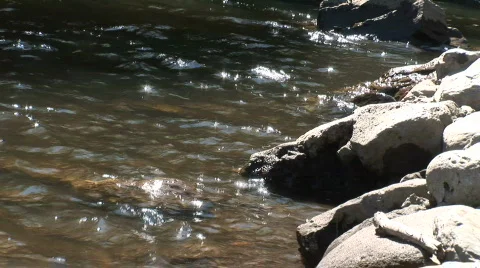 Sun glistens on water with rocks Stock Footage