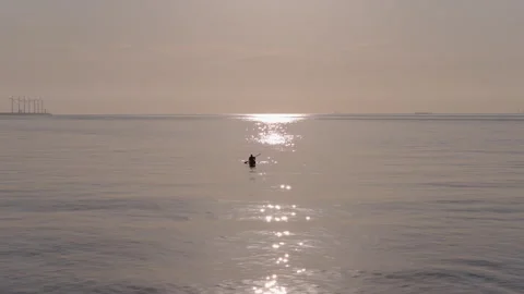 Sun glitter reflection on calm ocean surface with silhouette of kayaker Stock-Footage 345114591