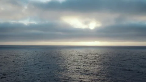 Sun glowing behind clouds over the open ocean Video stock 347825699