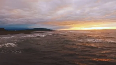 The sun goes below the horizon. Sunset. The rocky island is washed by the waves Stock Footage 72766921