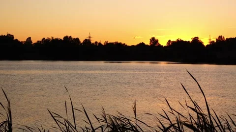Sun goes beyond horizon against background of large river and electric poles. Stock Footage 212958513