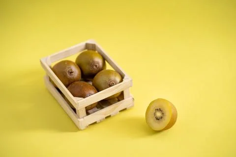 Sun gold kiwi in wooden fruit crate on a yellow background Stock Photos