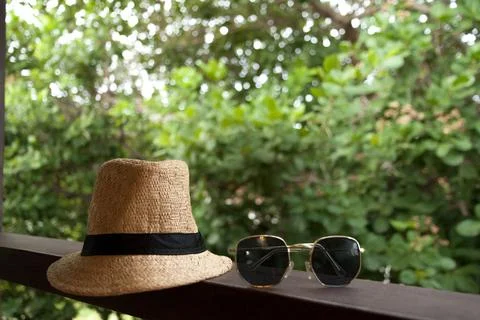 Sun hat and sunglasses on background with trees. Summer vacation at the inn.  Stock-Fotos