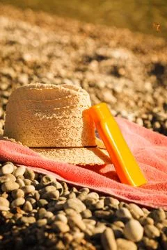 Sun hat and sunscreen on stone beach Stock Photos