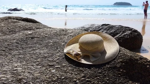 The sun hat is placed on a rocky beach on the beach Stock-Footage 77622970