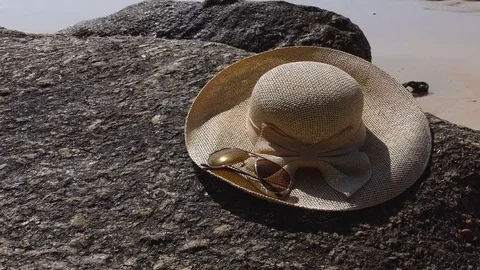 The sun hat is placed on a rocky beach on the beach 库存影片 77622984