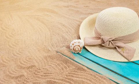 Sun hat with seashell and starfish on blue wooden board on sandy beach Stock Photos