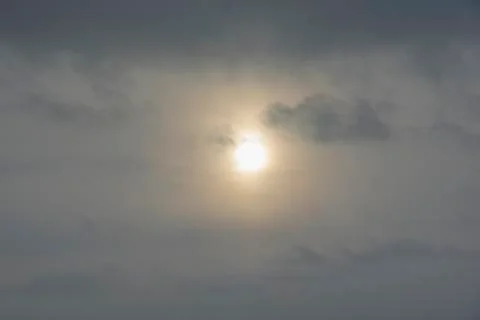 The sun hid behind the gray clouds on gloomy day Stock Photos