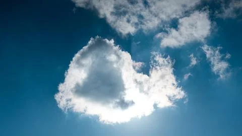 Sun hidden behind cloud in blue sky. Stock Photos